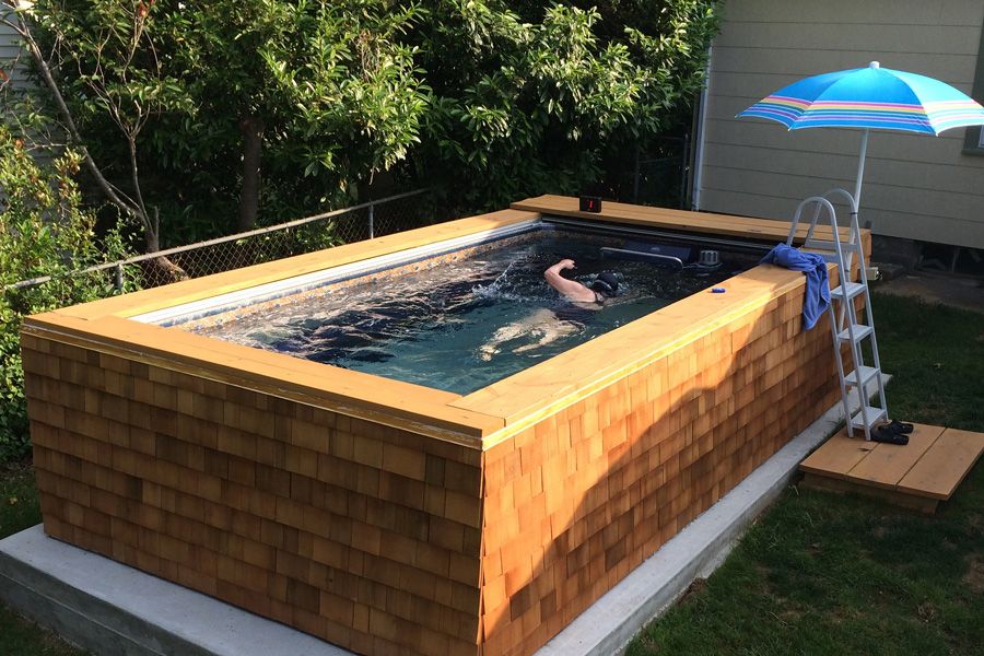 A picture of a woman swimming against the current in an above-ground, backyard pool.