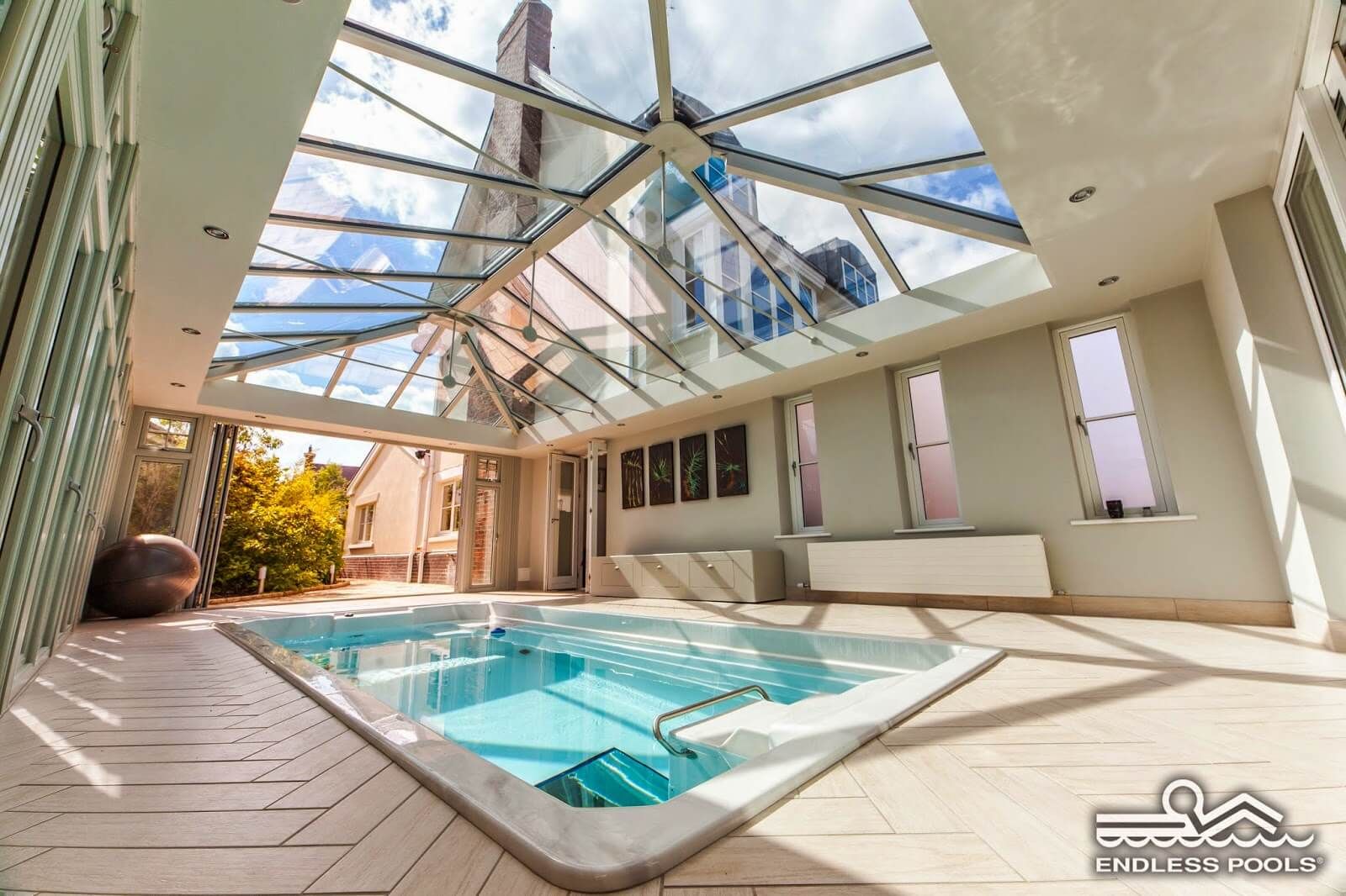 a fully in-ground Endless Pools Swim Spa under a glass roof