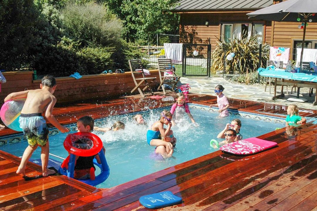 A picture of several kids celebrating a birthday party in a pool with a variety of pool toys.