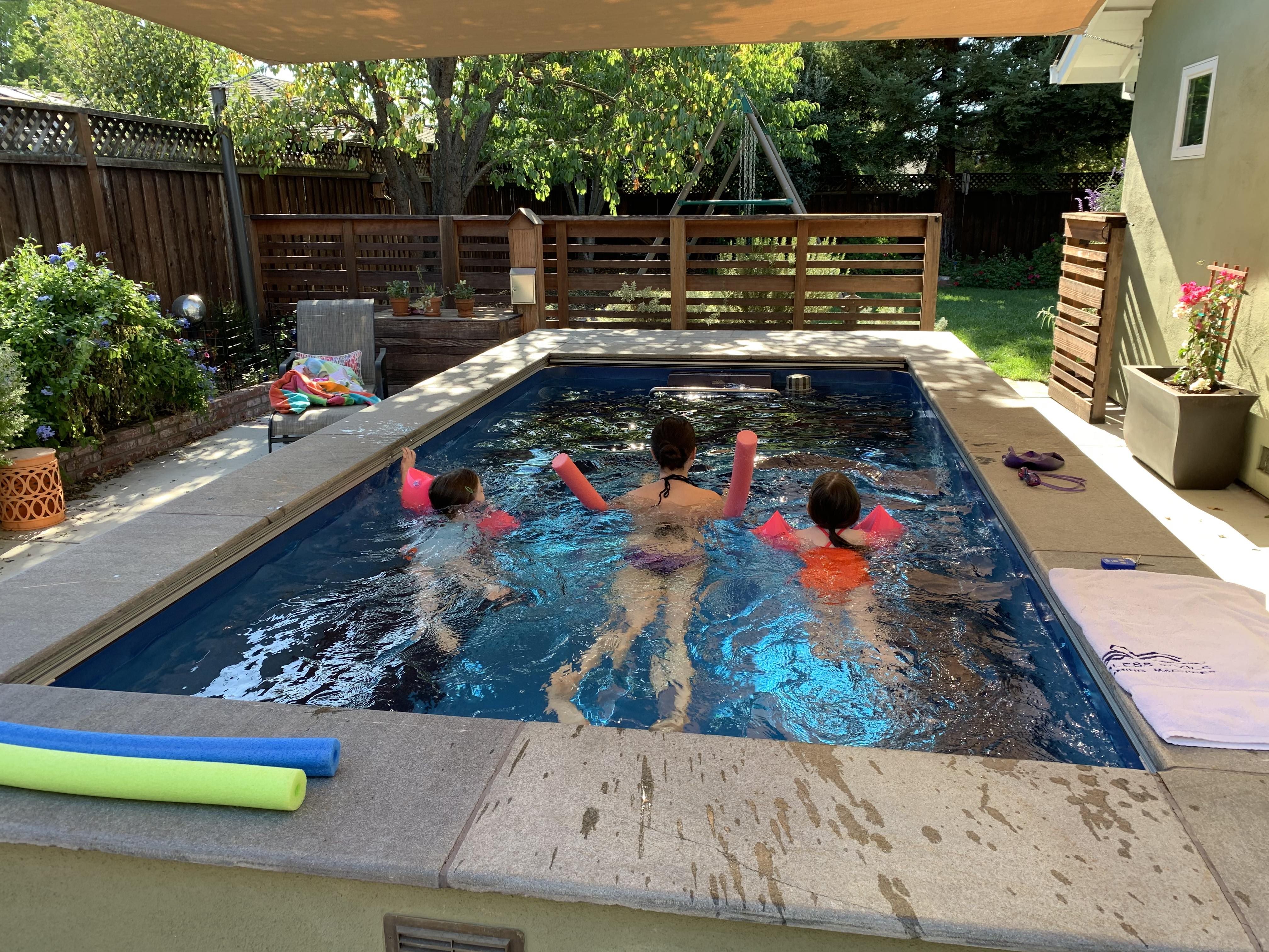 A picture of a woman and her two children swimming against the current with flotation devices.