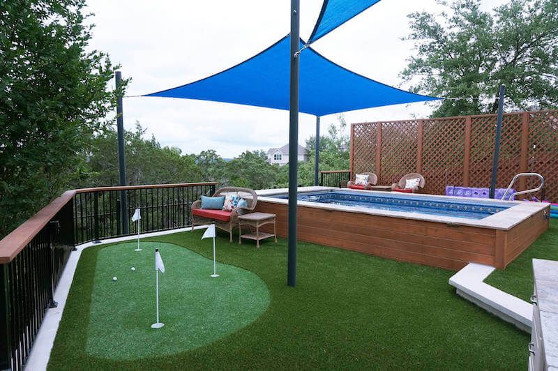 A picture of a beautiful outdoor space, complete with a pool, outdoor furniture, and even mini-golf.