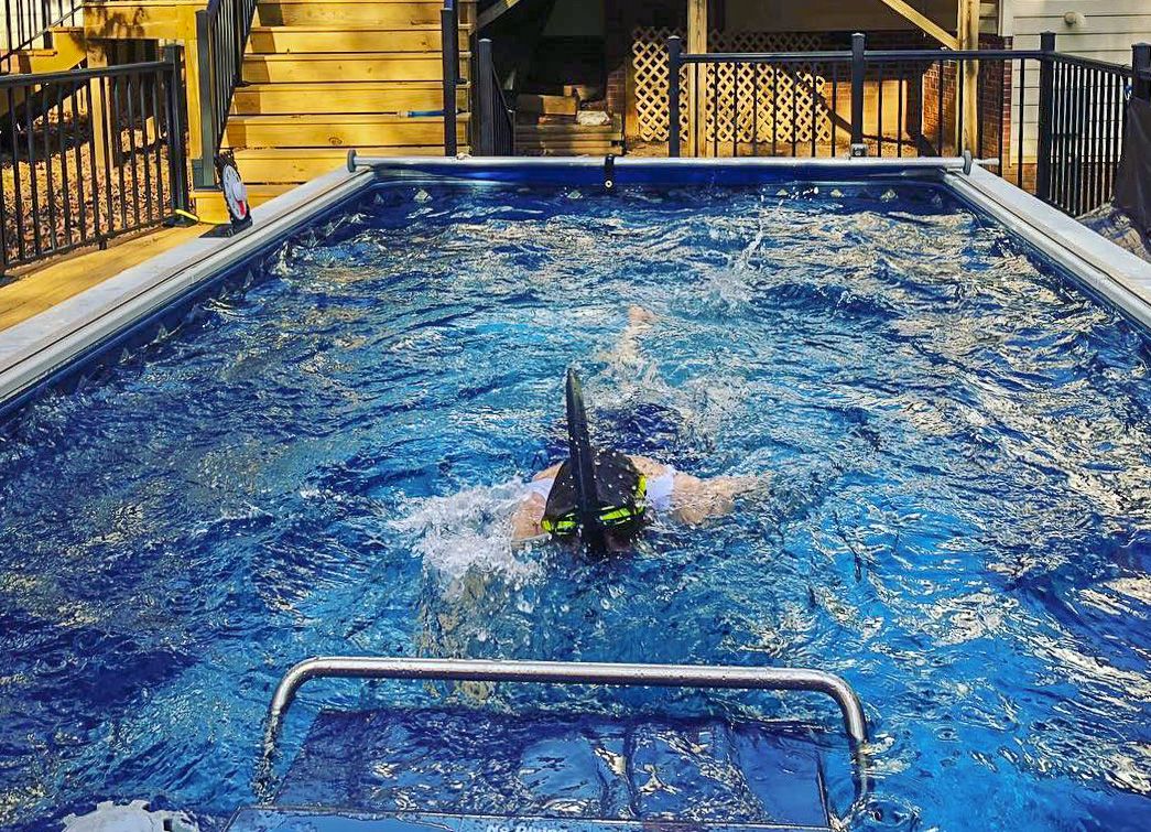 A picture of a woman swimming facedown against the endless current in a deck pool.