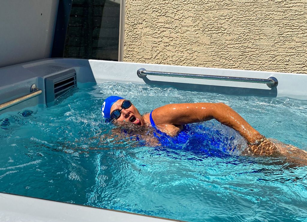 A picture of a woman coming up for air as she swims against the current in her above-ground pool.